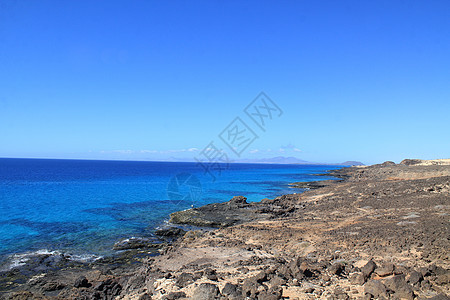 带白泡沫的动荡海洋波浪击打沿海石块 Fuert蓝色晴天天空海滩侵蚀海浪海岸荒野悬崖编队图片