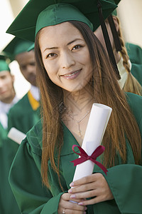 持有有背景朋友的文凭的女性毕业生肖像图象;在2001年12月1日图片