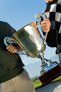 两名男性高尔夫球手在高尔夫球场上持有奖杯图片