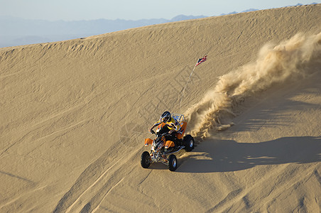 在沙漠沙丘上骑ATV的年轻人图片