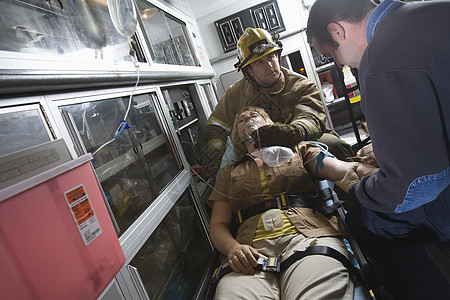 消防员和急救队医生在救护车中帮助受伤妇女图片