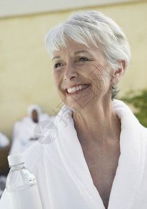 穿着浴袍的年长妇女微笑在白日中图片