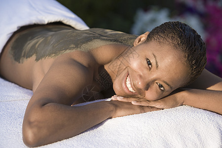 一名非洲裔美国妇女躺在按摩床上的肖像 背上涂满泥布的泥包图片