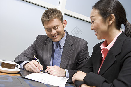 快乐的商务人士在办公室与亚洲女商务人士签订合同图片素材