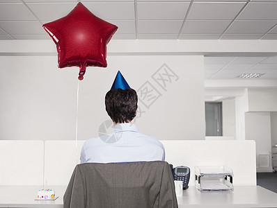 看见一个戴着党帽的男人 被红气球蒙在办公室里单独工作图片
