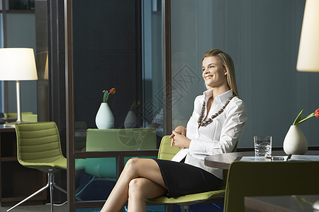 坐在办公室 笑着微笑的年轻女商务人士图片