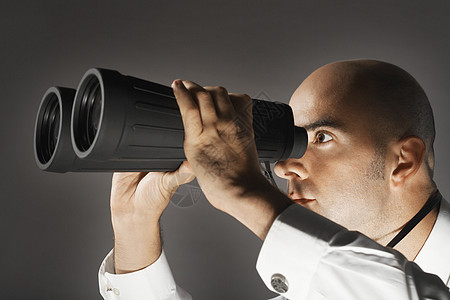 一名商务人士在灰色背景下通过大型望远镜进行近距离检查 以观察公司搜索人士办公室水平管理人员棱镜震惊工人秃顶图片