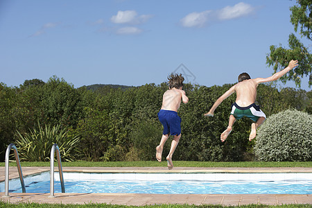 两名不穿衣服男孩跳进游泳池的全长后方视角图片