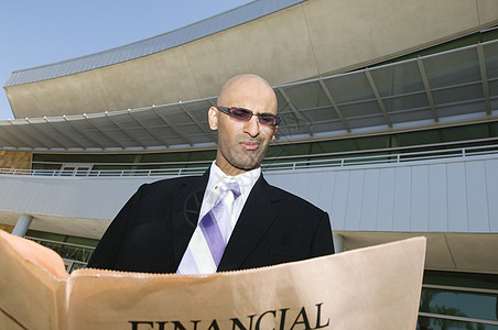 阅读金融报纸的印度商务人士 背景是大楼图片