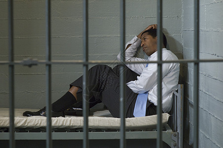 监狱犯人关押在牢房中床上的成年男子情绪刑事焦虑痛苦惩罚白领黑人商务法制领带背景