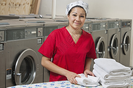 一名西班牙裔女性雇员在洗衣店用毛巾的肖像图片