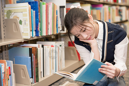 女人在书架附近看书教育女性女士地面女孩蓝色大学页数教科书图书馆图片