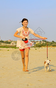 女孩与她的狗一起在沙滩上奔跑自由蓝色猎犬乐趣微笑跑步晴天喜悦宠物小狗图片