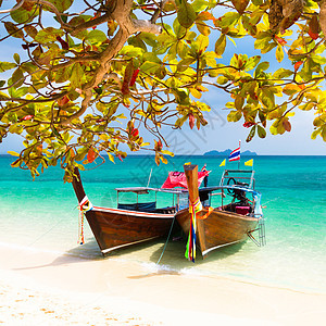 热带海滩上的木船太阳情调天空假期海洋海岸旅行异国蓝色游客图片