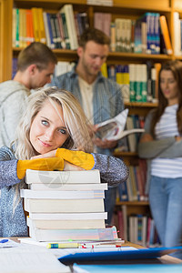 拥有大量书籍的女学生 而在图书馆有其他背景知识的女学生文学金发学习金发女郎团体男性女性书架浅色教科书图片