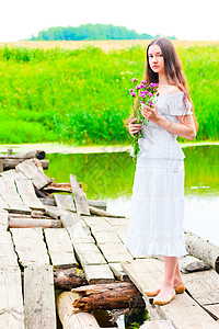 女孩在一座旧木桥上 用一束花束图片