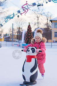 可爱的小女孩在冰场滑冰小姑娘溜冰场手套运动生活方式孩子微笑女性企鹅溜冰者图片