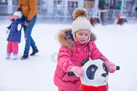 可爱女孩滑冰的肖像 她父亲和妹妹在冰雪背景上溜冰速度孩子微笑冰鞋幸福企鹅溜冰者运动手套小姑娘图片