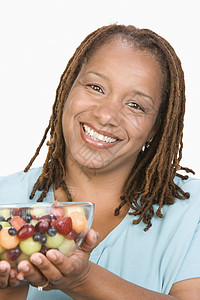 中成年超重女性的肖像 拿着碗机果沙拉和微笑近身图片