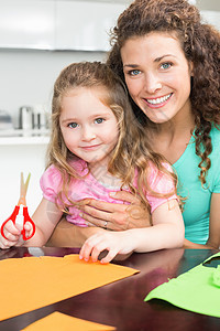 快乐的小女孩做纸面形状 和妈妈在桌子上图片