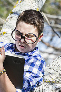 在树林里看书的学生男孩 和他一起读一本书图片