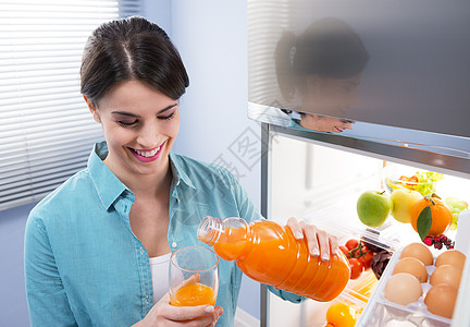 家用冰箱笑着微笑的妇女快乐瓶子女士果汁厨房女性电子魅力房子设备背景