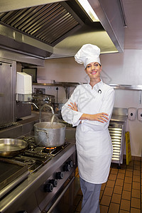 厨房中手交叉的微笑女性厨师火焰双手白人职业餐厅制服平底锅工作火炉双臂图片
