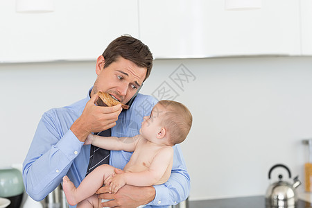 忙碌的父亲在工作前抱着儿子 吃烤面包家庭孩子抢夺厨房男性房子单身住所父母婴儿图片