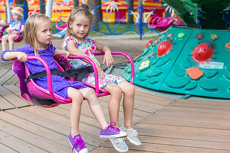 两个可爱的小妹妹 在公园骑着旋转木马娱乐节日姐妹微笑手势狂欢操场情绪童年木马图片
