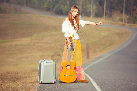 嬉皮女孩搭便车音乐家运输女孩女士游客国家街道拇指女性旅行图片