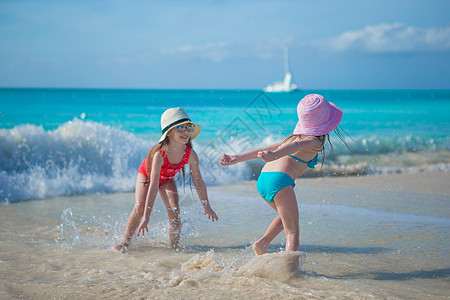 可爱的小女孩在异国海滩浅水中玩耍太阳旅游支撑乐趣女孩晴天旅行海岸线女士孩子图片