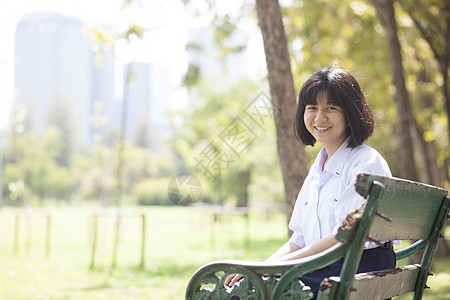 坐在长椅上的女学生乐趣青年闲暇女士说谎头发学习女孩校园微笑图片