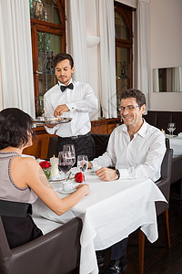 餐馆里微笑的年轻夫妇女性菜单服务员男人服务午餐饭厅夫妻社交奢华图片