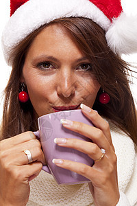 穿着圣诞老人帽子的冷酷年轻女人 喝着咖啡茶食物女士黑发庆典杯子饮料派对巧克力假期微笑图片