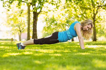 金发美女在公园里做俯卧撑阳光慢跑者绿地运动服浅色调子金发女郎头发闲暇赛跑者图片