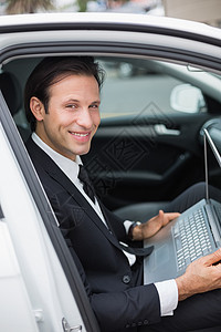 在驾驶座上工作的商家 司机男性技术套装人士驾驶笔记本汽车电脑微笑运输图片