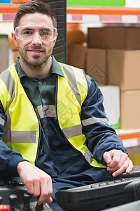 操作叉车机的微笑驾驶员男人仓库头盔工作黄色配送运输男性职业体力劳动者图片
