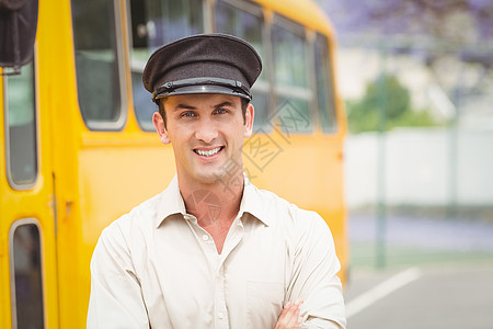 微笑的公共汽车司机看着相机客车学校黄色服务教练双臂城市运输男人帽子图片