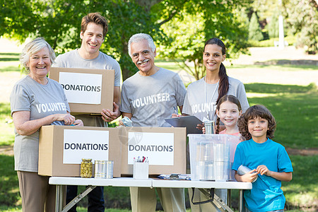 快乐的志愿者家庭将捐赠物品分离开来志愿童年环境男生兄弟社区食物兄弟姐妹盒子阳光图片
