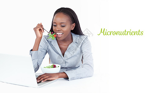 反对在吃沙拉时用笔记本电脑工作的女商务人士的微营养素图片
