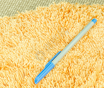 蓝笔在橙色毛发布地毯上柔软度头发纤维房子橙子羊皮宏观地面材料毛皮图片