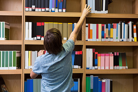 学生在图书馆书架上取书校园大学生大学高等教育学校知识男性男人采摘教育图片