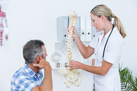 给病人看脊椎模型的医生按摩师讨论男性中心女性互动会议治疗师身体疼痛图片