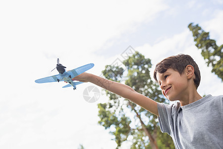 在公园玩玩具飞机的男孩头发旅行微笑活动树木男生男性乐趣短发闲暇图片