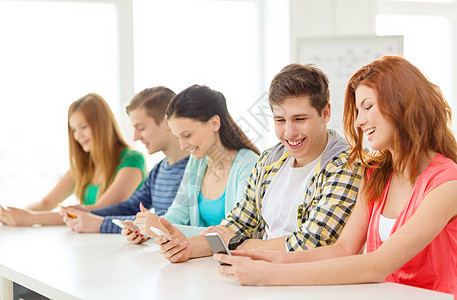 学校里带智能手机 微笑着微笑的学生课堂教育女孩团体图书馆大学团队男生聊天视频图片