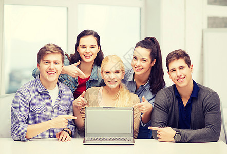 带着微笑的学生指向空白的挂顶屏幕女性电脑男孩们女孩们团队互联网技术男人展示团体图片