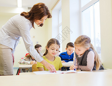 课堂上学生写字考试组数孩子们班级小学生老师男孩们帮助女学生桌子学校生活图片