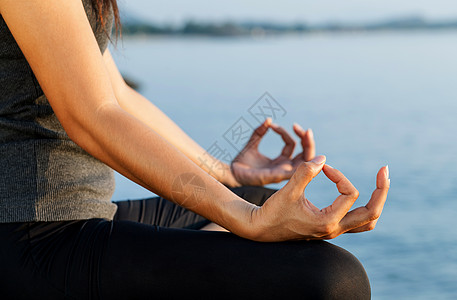 湖边瑜伽在热带海滩的瑜伽姿势中冥想的女人女士福利头脑女孩天空岩石日落生活太阳温泉背景