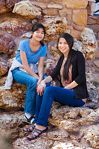 两个年轻女孩坐在一起 坐在岩石石座椅上图片