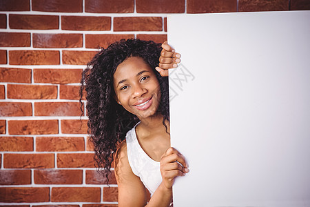 带着白板的笑容女人卷发女性黑色女士海报红砖服装黑发休闲微笑图片